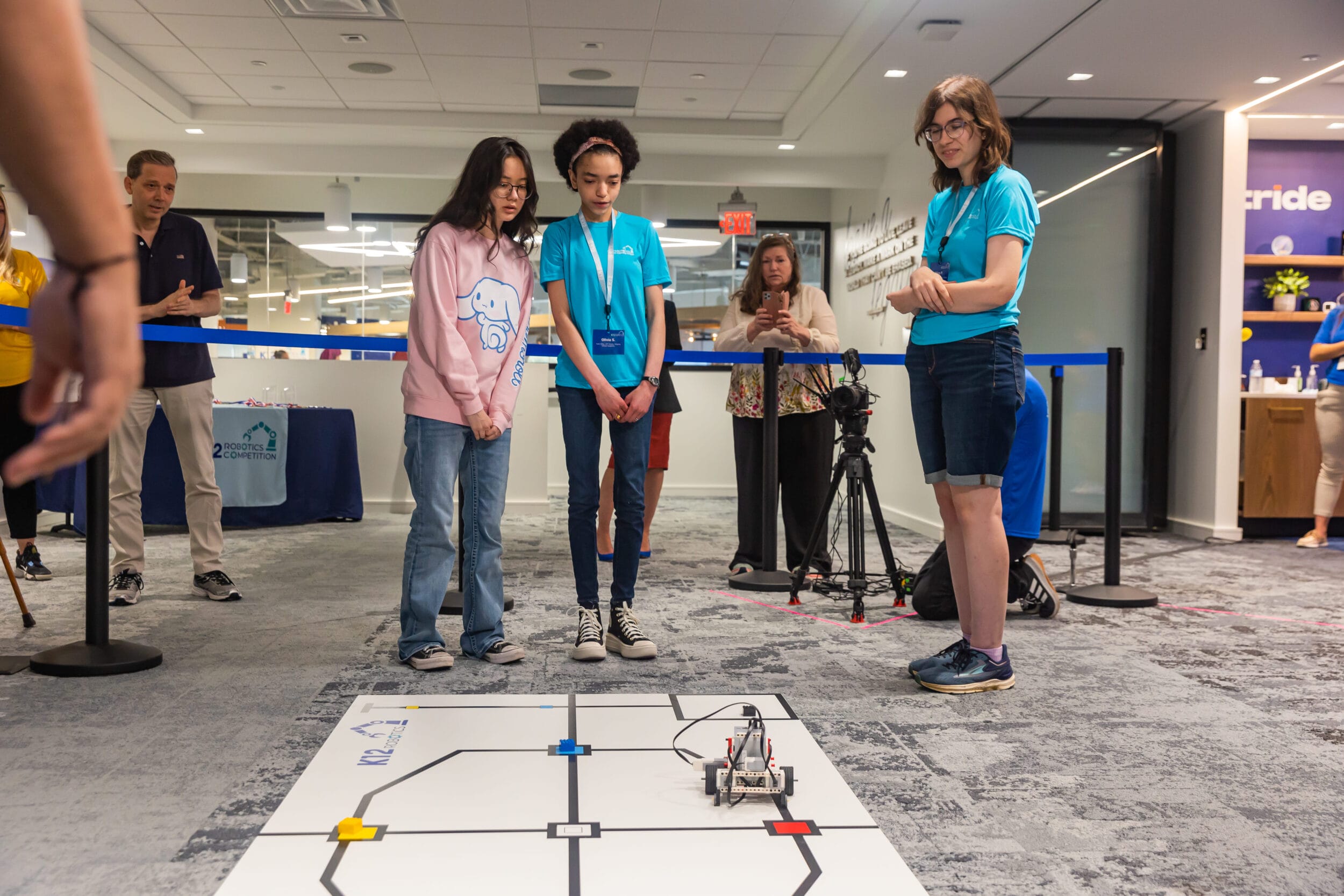 A group of girls gathered around a robot, engaging in conversation and exploring its features with curiosity.