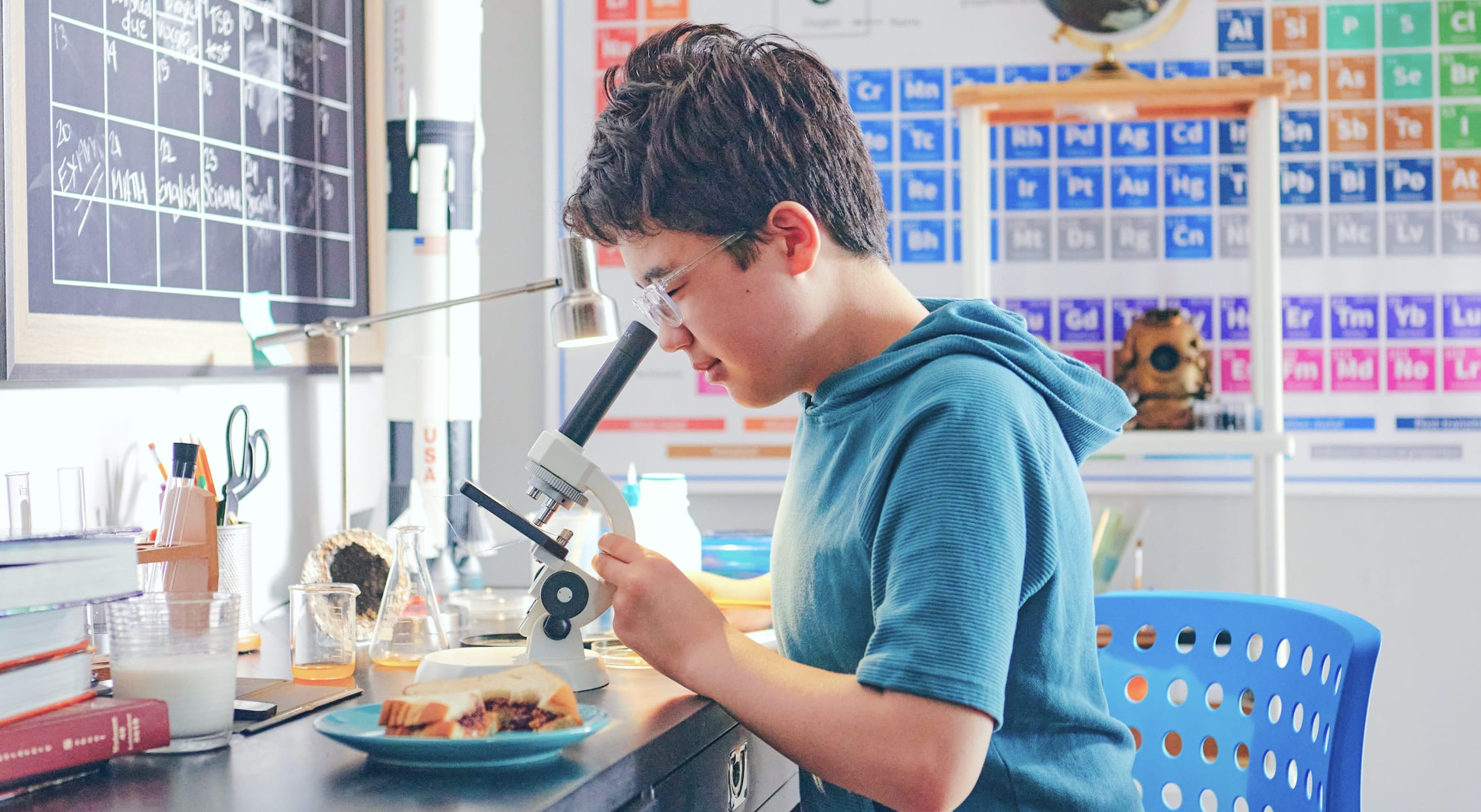 A boy examines a microscope in a classroom, showcasing curiosity and engagement in scientific exploration.