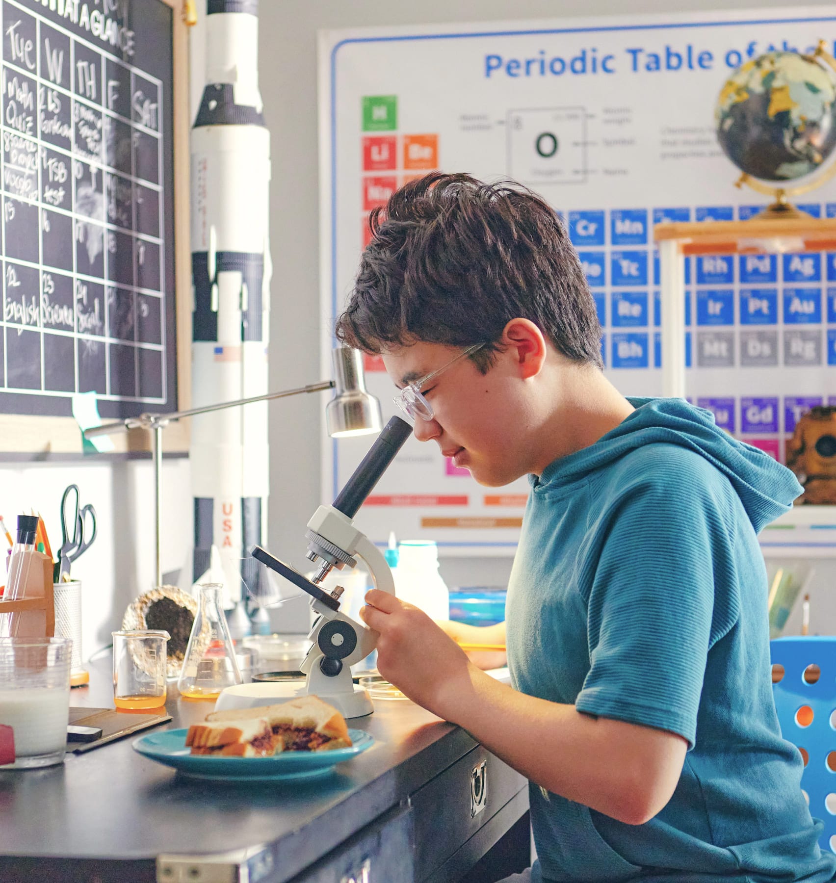 A young boy examines a microscope intently in a well-equipped science laboratory.