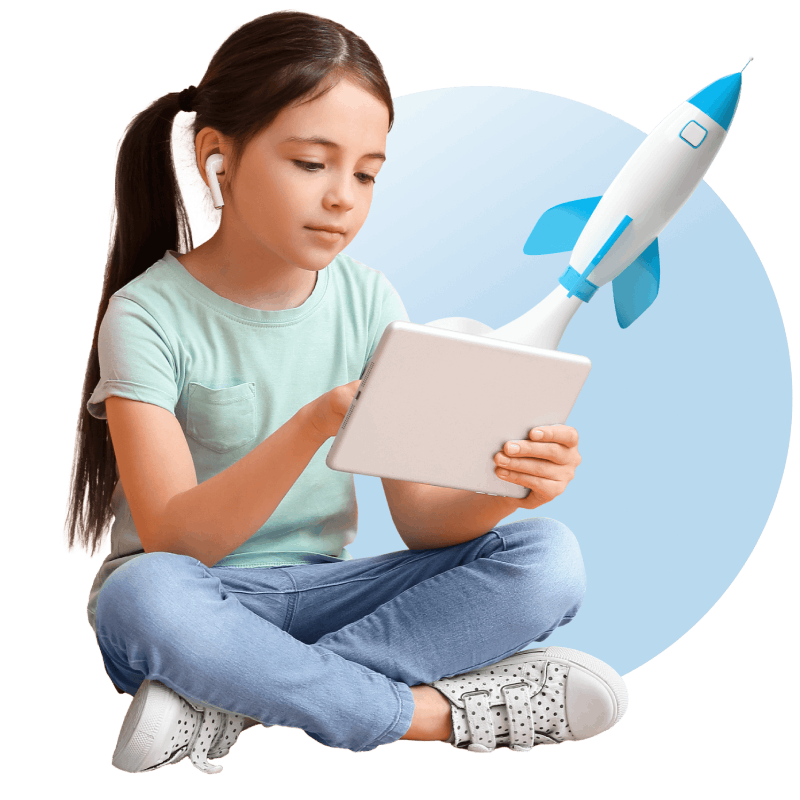 A girl sits on the floor, engaged with a tablet computer, while a colorful rocket is positioned nearby.