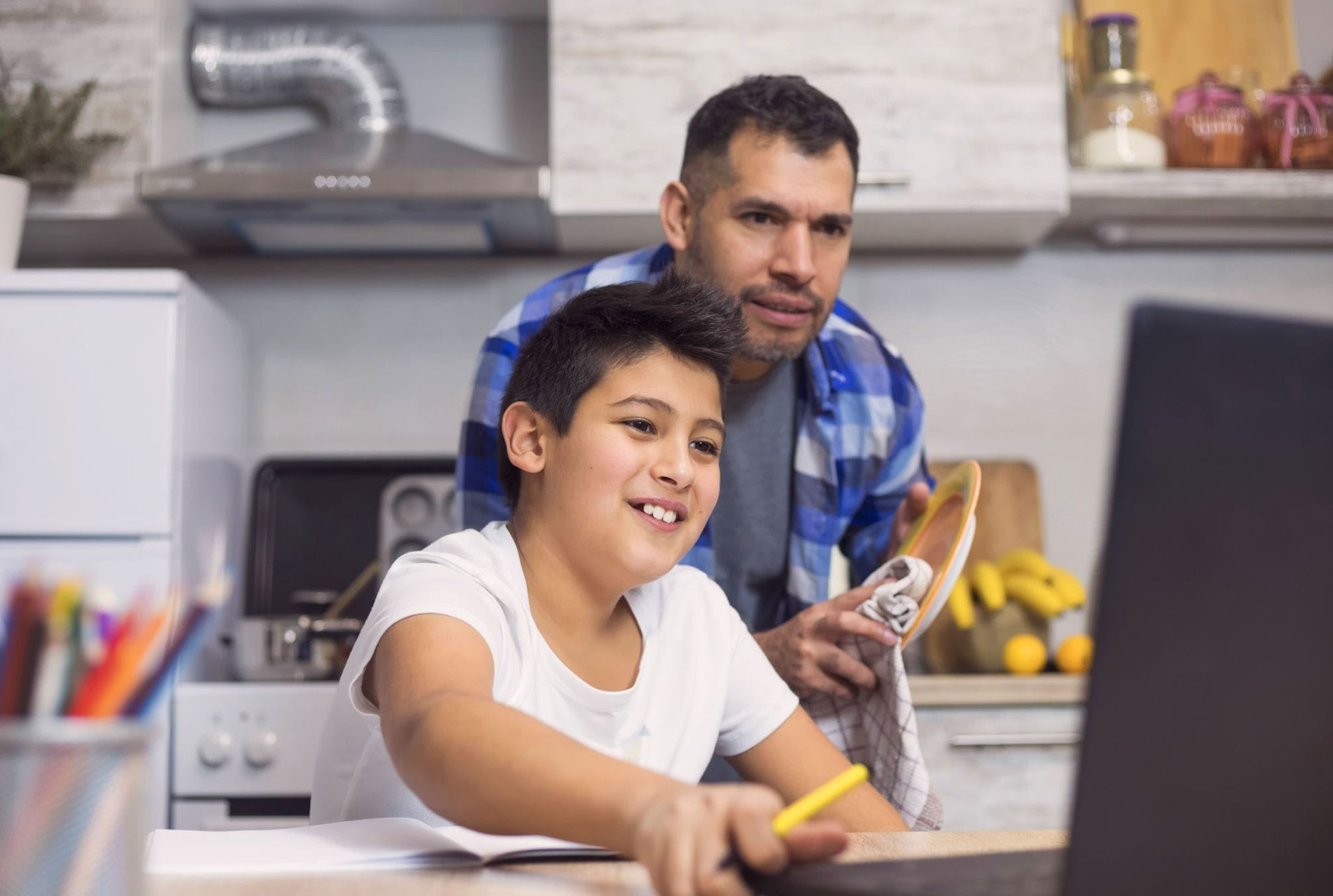 A man and a boy collaborate on a laptop, engaged in a productive learning experience together.