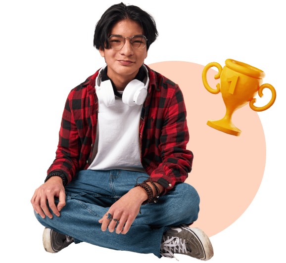 A young man sitting on the floor, smiling proudly while holding a trophy in his hands.