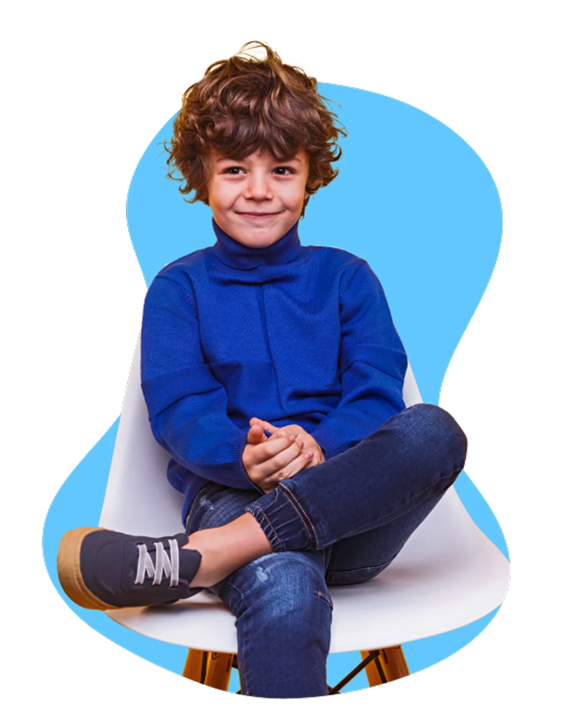 Young child with curly brown hair sits cross-legged on a white chair, wearing a blue sweater and jeans. The background is a soft blue, conveying a cheerful tone.