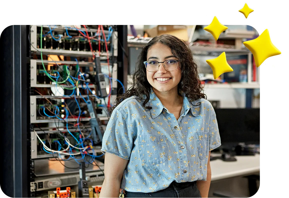 A smiling woman with curly hair and glasses stands in front of a server rack filled with colorful cables. She wears a blue floral shirt. Yellow star graphics hover nearby, suggesting a positive, hopeful atmosphere.