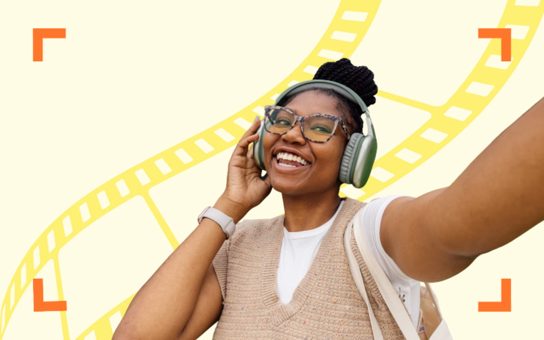 A joyful person wearing large green headphones takes a selfie, smiling brightly. They're in a tan sweater with a yellow filmstrip design background.